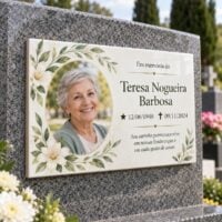 Placa memorial em cerâmica clara, com foto em moldura redonda e folhagem verde, fixada em lápide