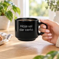 Mão segurando a xícara preta personalizada com a frase Hoje vai dar certo, mostrando o tamanho real